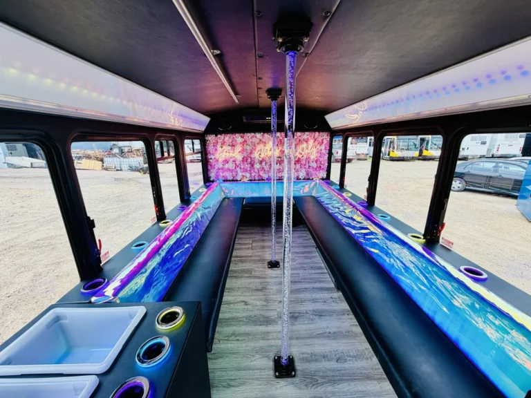 Wide interior view of the Mini Unicorn mini party bus with poles and wrap-print benches
