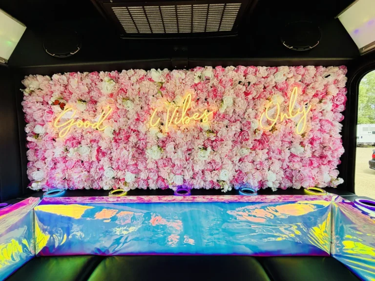 Pink flower wall with glowing neon sign inside The Mini Unicorn party bus in Minneapolis